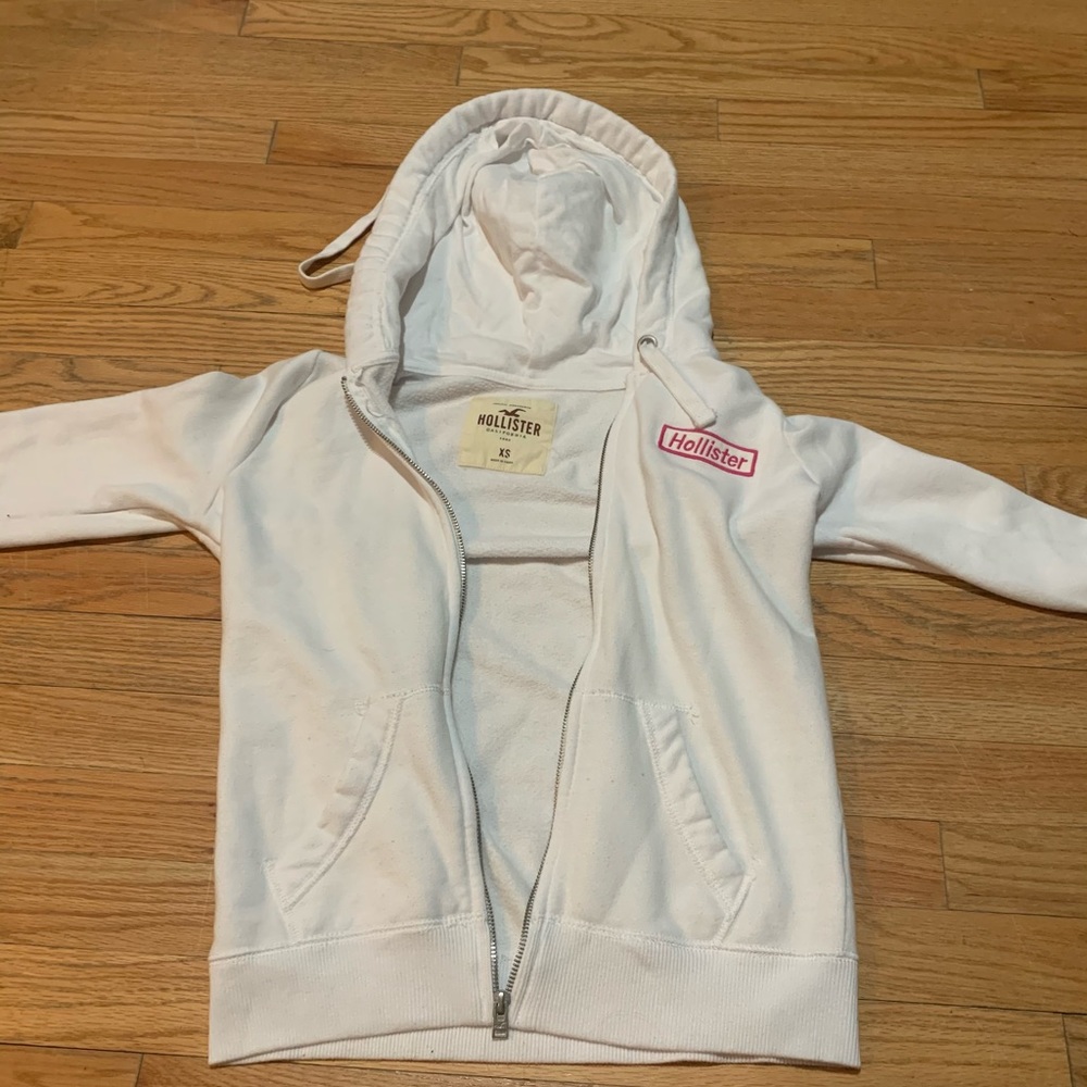 Hollister white zip up with pink embroidery on sleeves and one side on chest